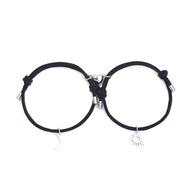 Duo de bracelets cordon noirs avec charms soleil et lune argentés, fermoir métal.