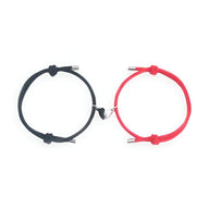Duo de bracelets cordon noir et rouge avec cœurs magnétiques argentés, design simple et élégant.