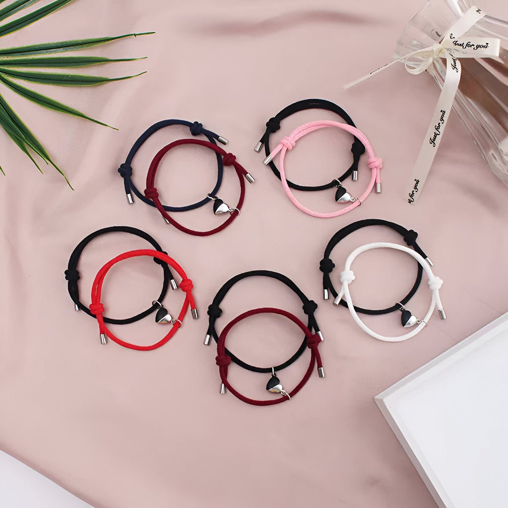 Cinq paires de bracelets cordon avec cœurs aimantés en noir et blanc, noir, noir et rose, noir et rouge, rouge sur fond rose .