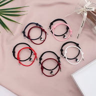 Cinq paires de bracelets cordon avec cœurs aimantés en noir et blanc, noir, noir et rose, noir et rouge, rouge sur fond rose .