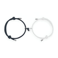 Duo de bracelets cordon noir et blanc avec cœur magnétique argenté au centre.