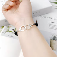 Bracelet cordon noir avec menottes argentées ajustable porté au poignet féminin.