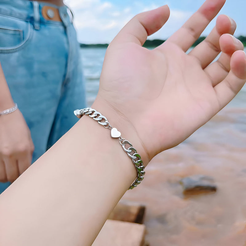 Bracelet argent en acier inoxydable avec motif cœur sur poignet, style chaîne élégante.