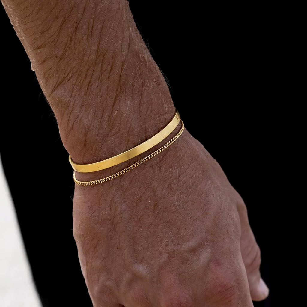 Duo de bracelets pour homme en acier inoxydable, jonc lisse doré et chaîne maille fine dorée.