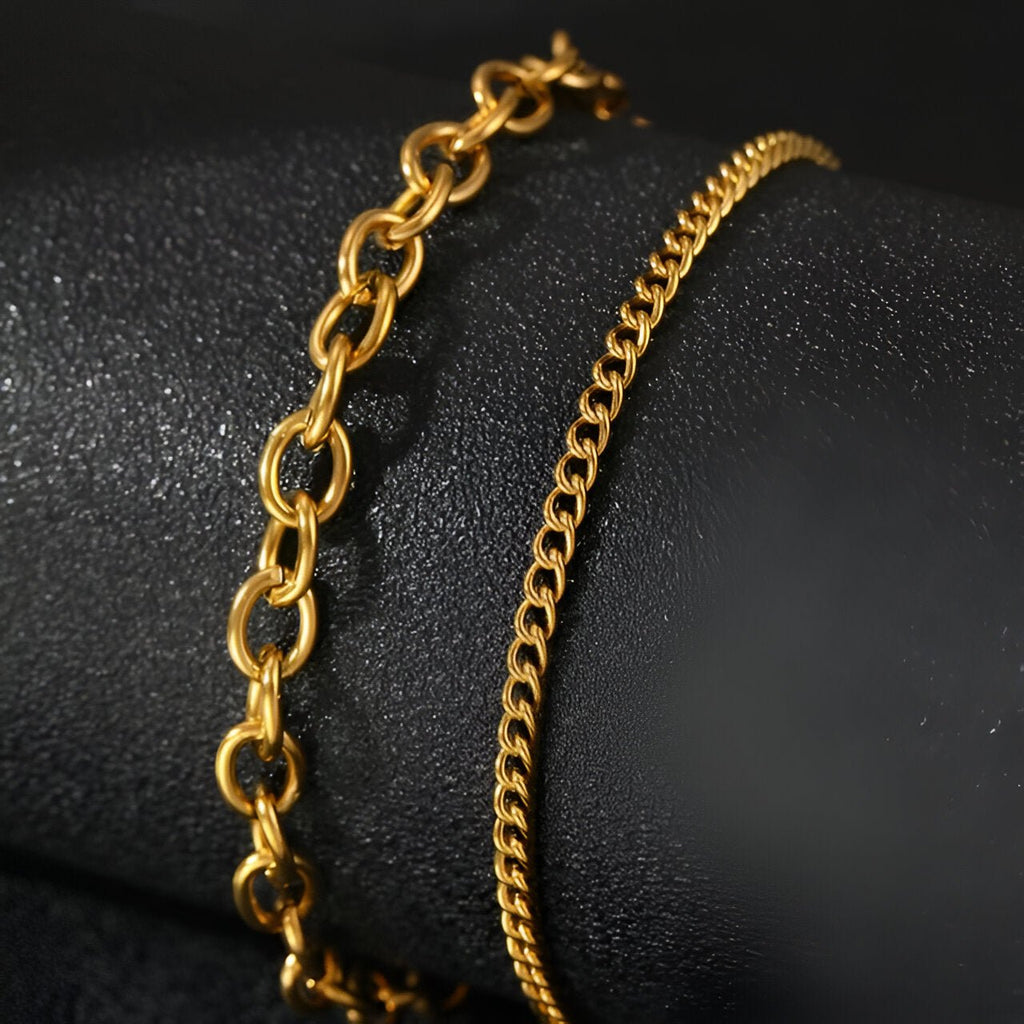 Duo de bracelets en acier inoxydable doré, un à maillons larges ovales, l'autre à maillons fins en chaîne serpentine.