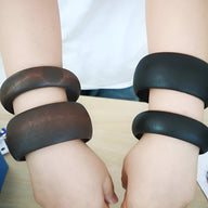 Duo de bracelets en bois naturel, larges, finition lisse, un noir et un marron, portés au poignet féminin.
