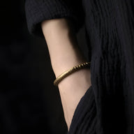 Duo de bracelets fins en cuivre et perles d’œil de tigre marron sur poignet féminin, style épuré.