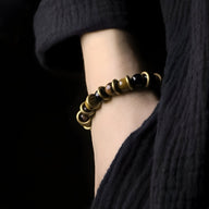 Bracelet duo en œil de tigre marron et cuivre lumineux porté au poignet femme, style naturel et élégant.