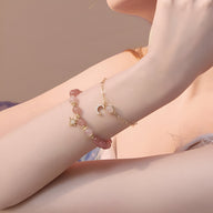 Duo de bracelets rose en pierres de cristal avec pendentifs étoile et lune en métal doré.