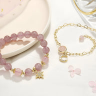 Duo de bracelets rose en pierres de cristal avec charms étoile et lune en métal doré.