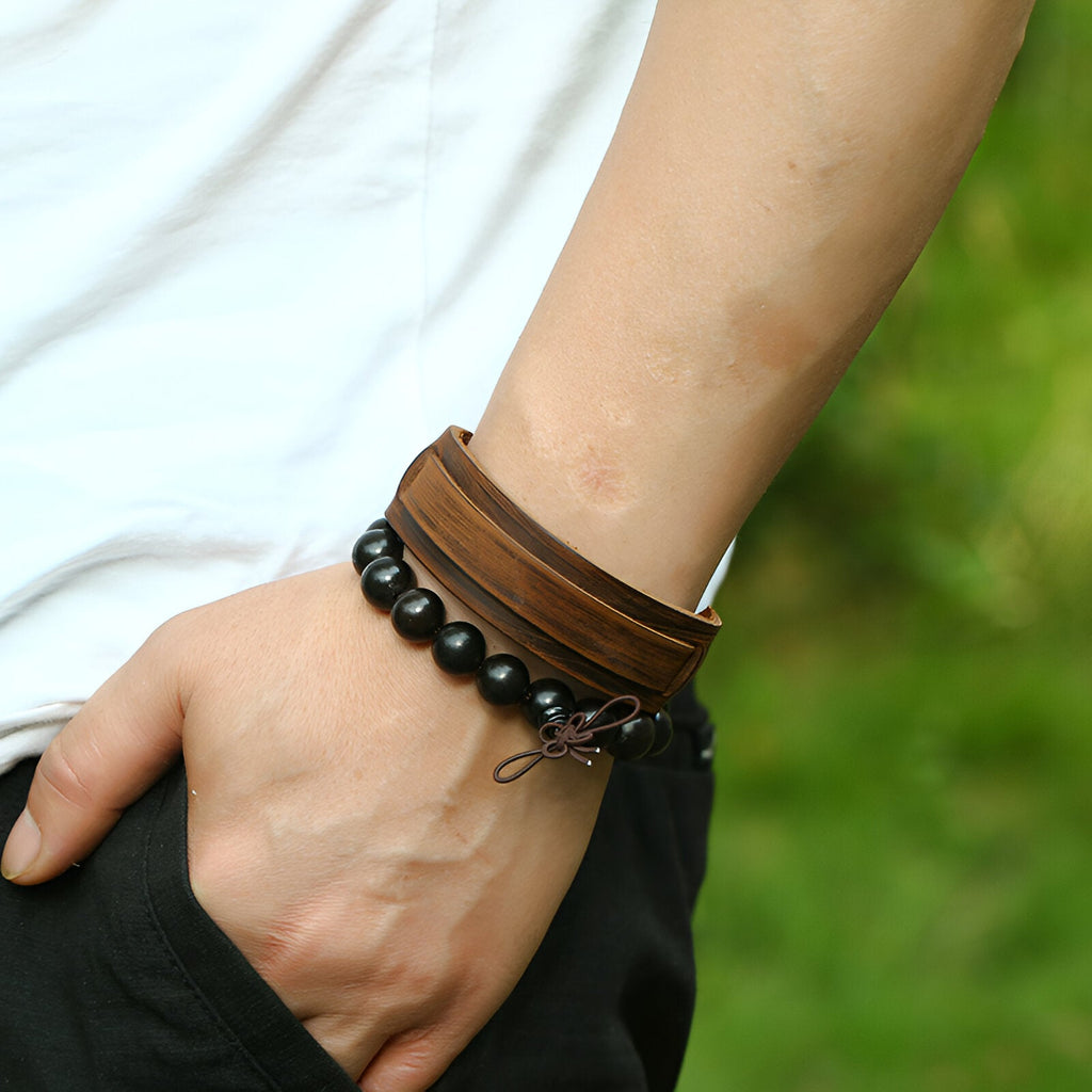 Duo de bracelets larges marron, cuir lisse et perles noires mates, style masculin moderne.