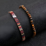 Duo de bracelets pour homme, l’un en perles naturelles marron et l’autre en fil ciré noir et rouge à motifs beige.