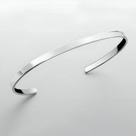 Bracelet jonc fin en acier inoxydable argenté avec finition polie et bords biseautés.