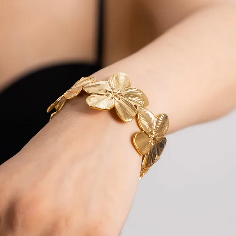 Bracelet manchette en acier inoxydable doré avec larges fleurs sculptées et finition brillante.