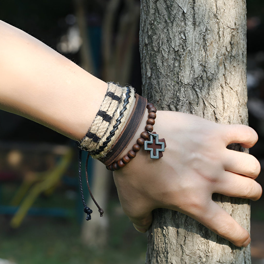 Ensemble de 4 bracelets marron en bois, cuir et corde avec un charm croix noir et beige.