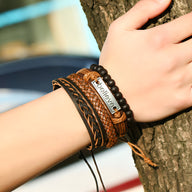 Ensemble de 4 bracelets marron en cuir et perles avec breloque "Believe" sur poignet.