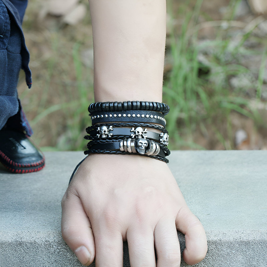 Ensemble de 4 bracelets noirs en cuir et bois avec têtes de mort métalliques pour homme.