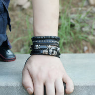 Ensemble de 4 bracelets noirs en cuir et bois avec têtes de mort métalliques pour homme.