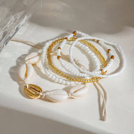 Ensemble de bracelets de cheville blancs avec coquillages naturels et perles fines dorées.