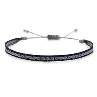 Bracelet tibétain noir avec motif argenté tissé et fermeture ajustable en corde noire.