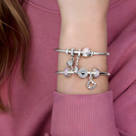 Bracelets argentés fins avec espaceurs et breloques éclatantes sur poignet féminin.