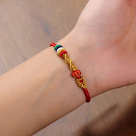 Bracelet serpent rouge en fil ciré avec perles turquoise jaune et rouge, style porte-bonheur.