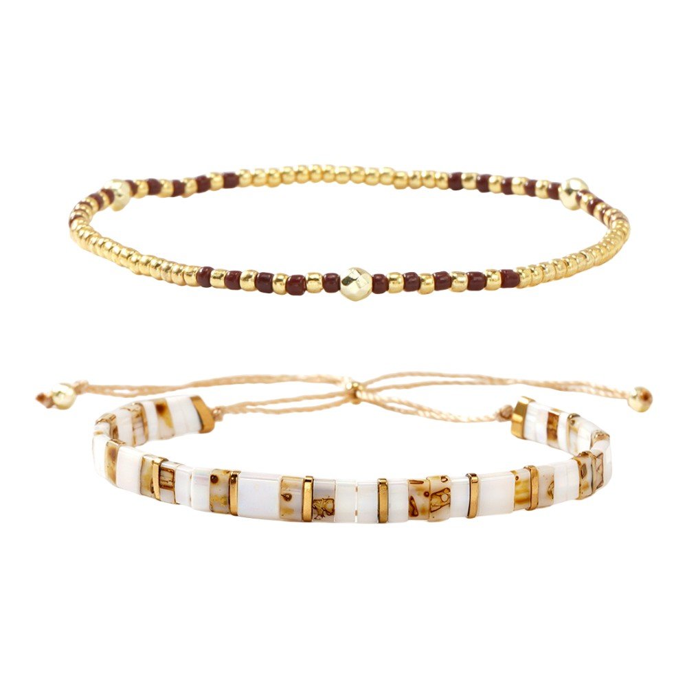 Set de deux bracelets bohème chic, perles dorées rondes fines et cubes marbrés blancs avec détails dorés, fermoir ajustable.