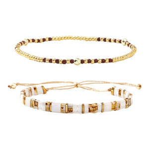 Set de deux bracelets bohème chic, perles dorées rondes fines et cubes marbrés blancs avec détails dorés, fermoir ajustable.