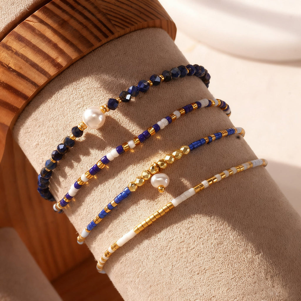 Set de quatre bracelets fins à perles bleu lapis lazuli, or mat et perles blanches, cordons coulissants ajustables, style.