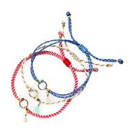 Trio de bracelets cordon bleu blanc rouge avec pompons et petits anneaux dorés.