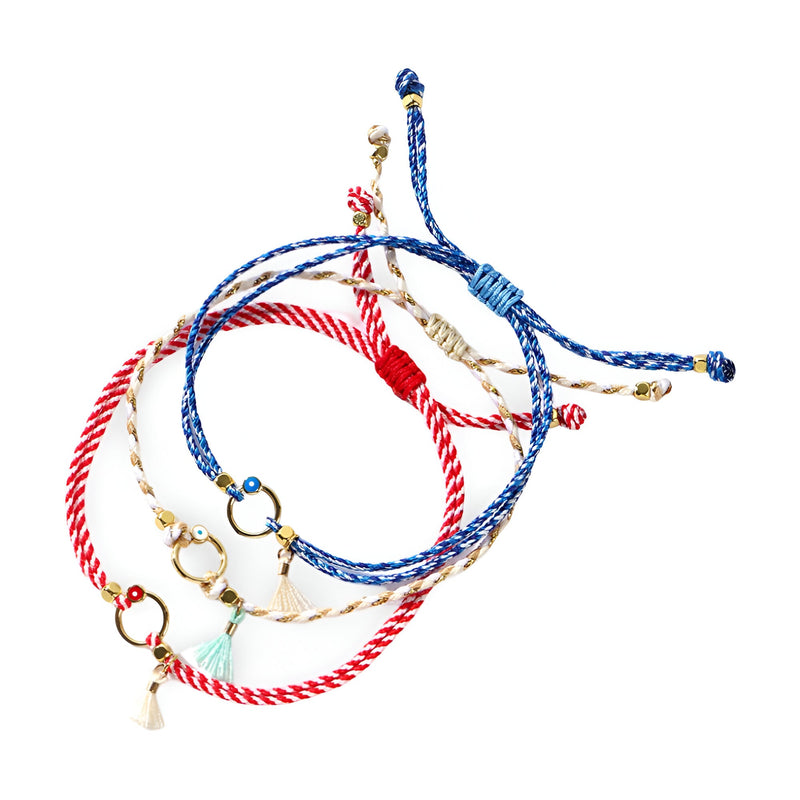 Trio de bracelets cordon bleu blanc rouge avec pompons et petits anneaux dorés.