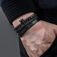 Trio de bracelets noirs en acier inoxydable avec motif couronne et détails gravés, style masculin élégant.