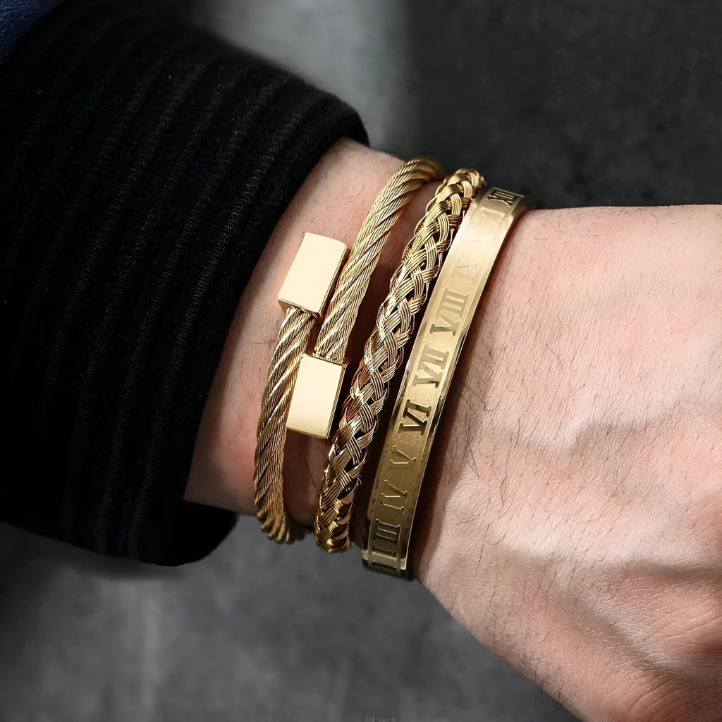 Trio de bracelets en acier inoxydable or, styles chaîne torsadée, maillons larges, et bracelet gravé chiffres romains.