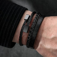 Trio de bracelets homme en acier inoxydable noir avec tresse, boucle carrée et gravure centrale.