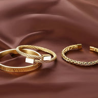 Trio de bracelets en acier inoxydable or jaune, finitions brossées et tressées, style masculin élégant.
