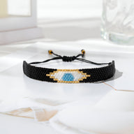 Bracelet trio perles noires japonaises avec œil de protection bleu, beiges et blanches, modèle Okile pour femme.