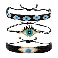 Trio de bracelets noirs en perles du Japon avec motifs œil protecteur bleu et blanc, fermetures à cordon ajustable.