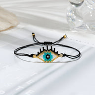 Trio de bracelets noirs en perles japonaises avec motif œil de protection bleu et beige.