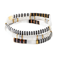 Trio de bracelets blancs en perles du Japon avec fils noirs, dorés et cuivrés entrelacés.