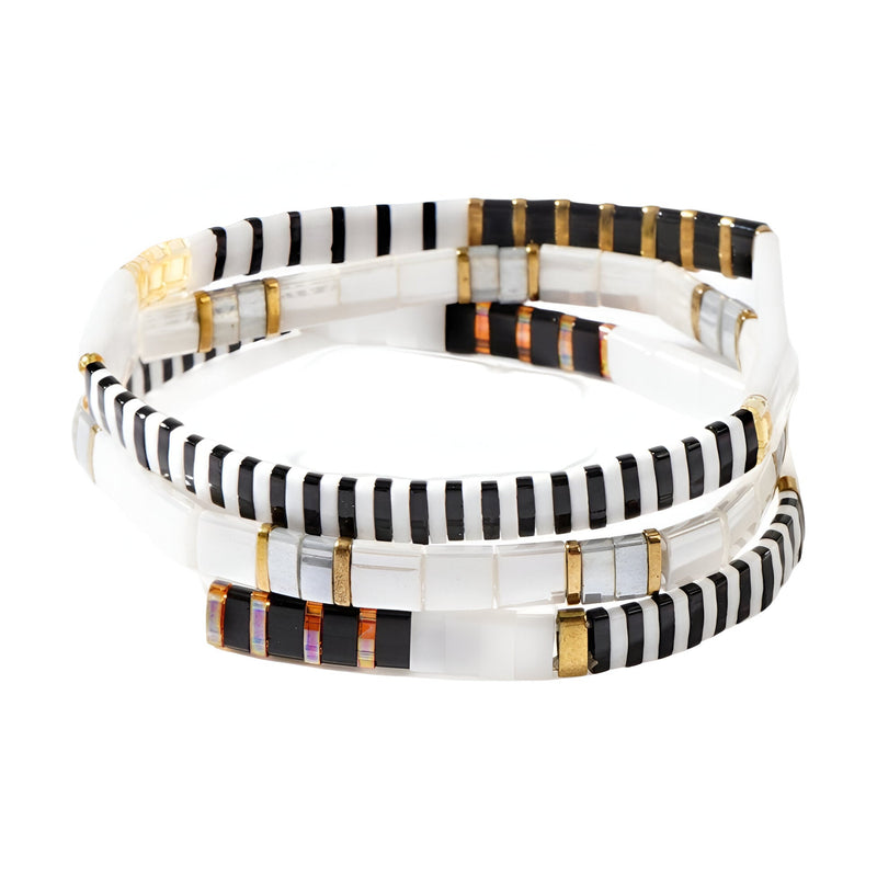 Trio de bracelets blancs en perles du Japon avec fils noirs, dorés et cuivrés entrelacés.