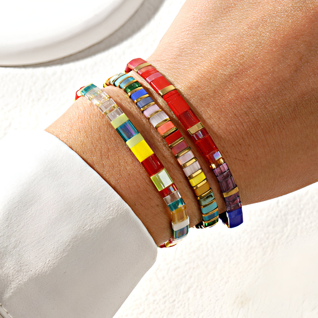 Trio de bracelets en perles multicolores fines, style japonais, porté au poignet féminin.