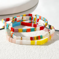 Trio de bracelets en perles multicolores carrées, style japonais, avec accents dorés.