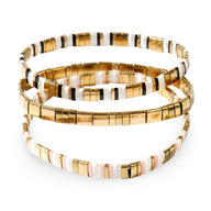 Trio de bracelets en perles japonaises dorées et blanches, style empilé élégant.