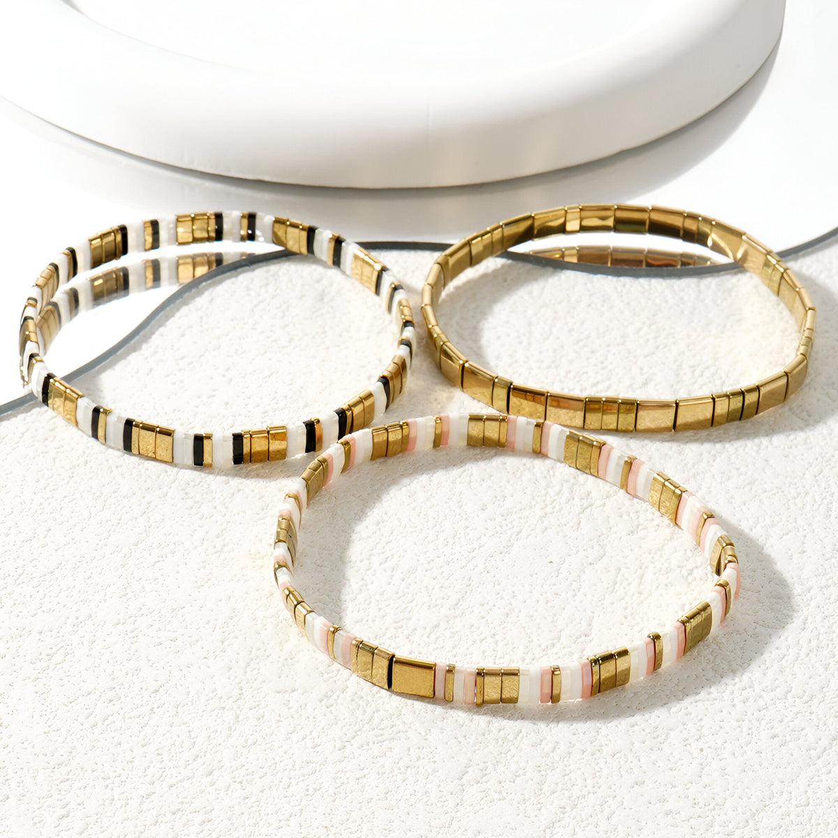 Trio de bracelets en perles japonaises or, blanc et rose, style minimaliste élégant.