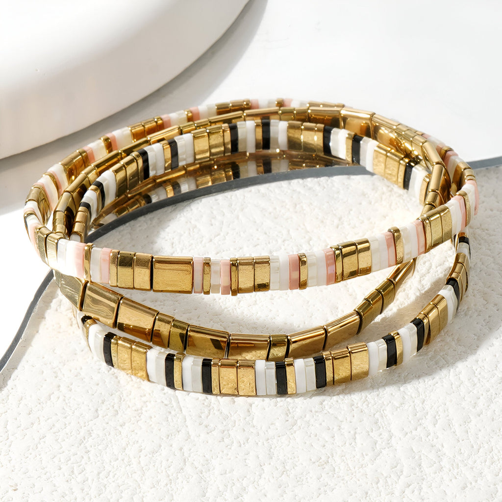 Trio de bracelets fines en perles dorées, blanches et noires, style japonais élégant.