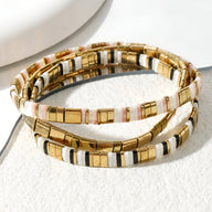 Trio de bracelets fines en perles dorées, blanches et noires, style japonais élégant.