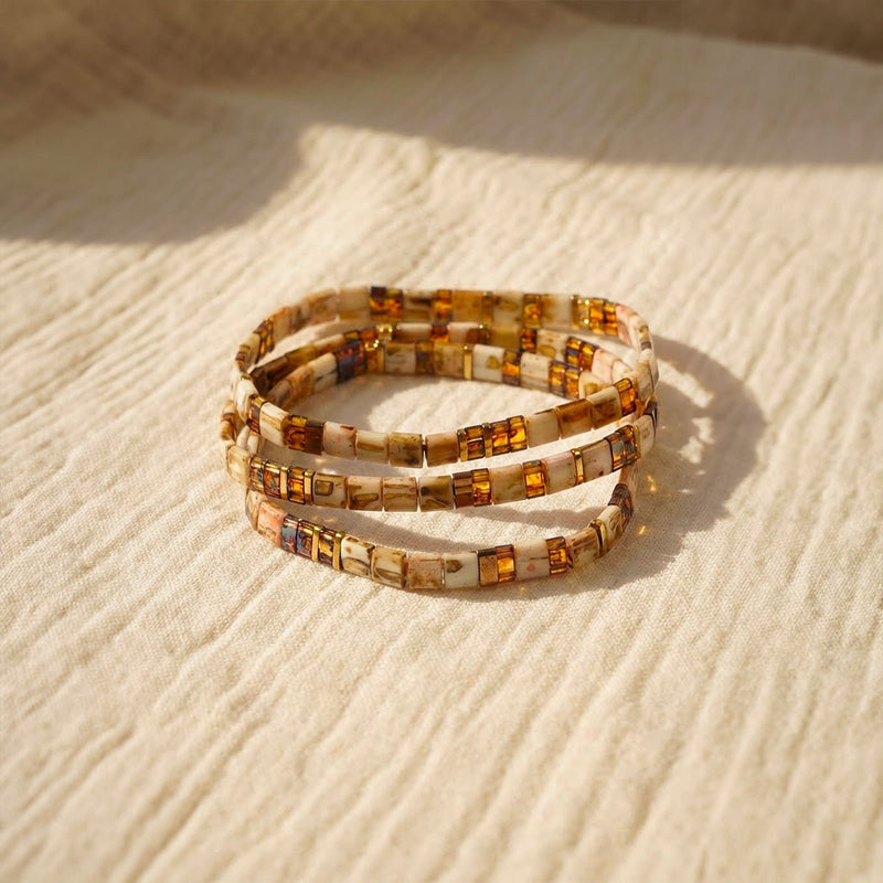 Trio de bracelets élastiques en perles japonaises caramel, nacrées avec motifs léopard dorés.
