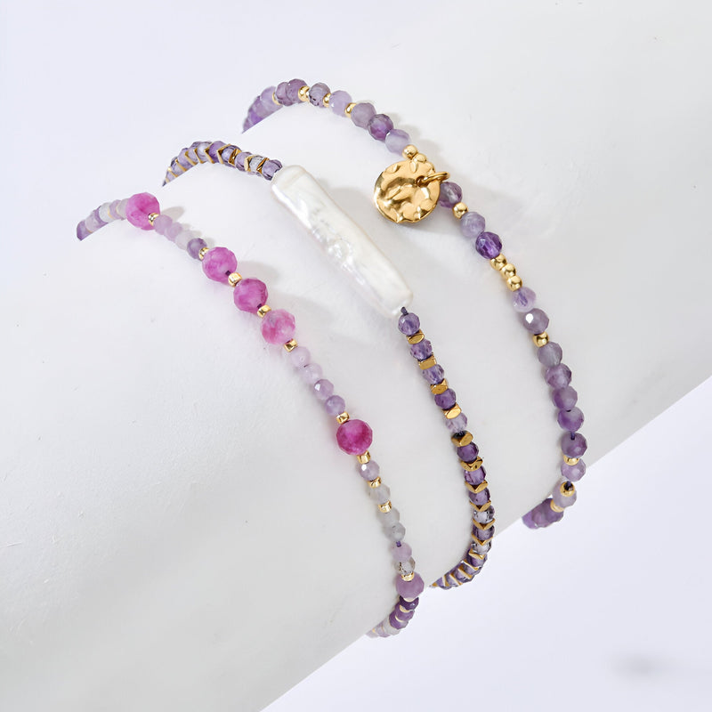 Trio de bracelets violets en pierre naturelle, perles rondes et nacre, ornements dorés délicats.