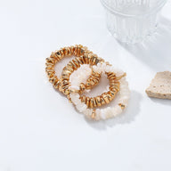 Trio de bracelets pour femme en métal doré avec perles blanches iridescentes et pierres naturelles translucides.