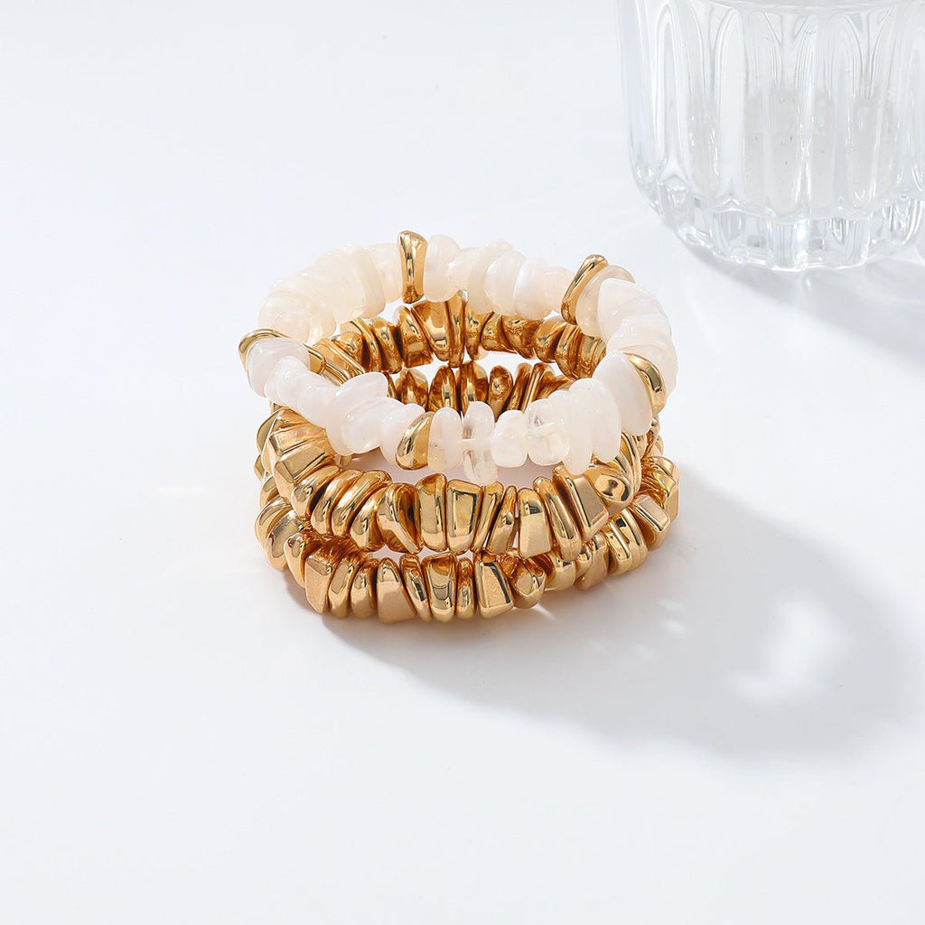 Trio de bracelets anneaux dorés et pierres blanches brillantes, style élégant et texturé.